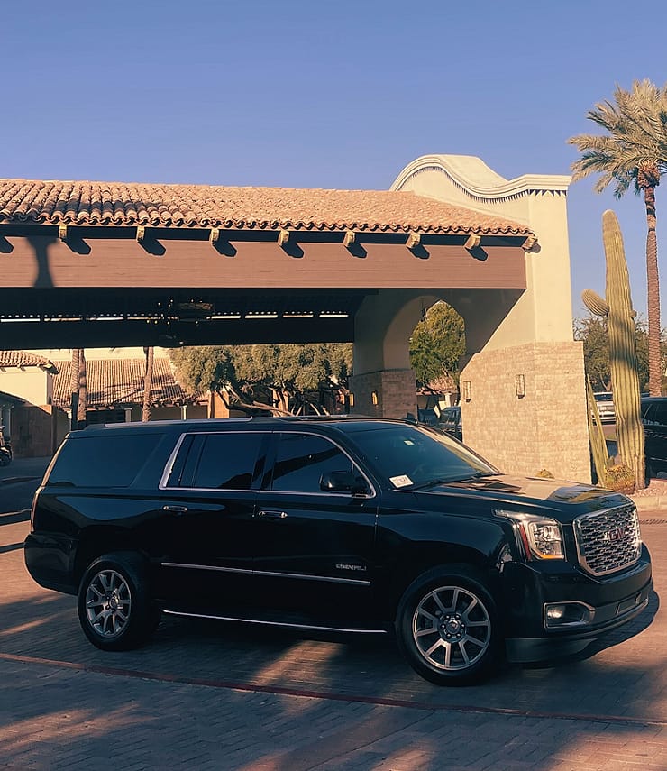 Side profile of a black GMC Yukon XL Denali at sunset with palm trees, Phoenix