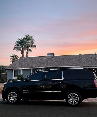 Side profile of a black GMC Yukon XL Denali at sunset with palm trees, Phoenix
