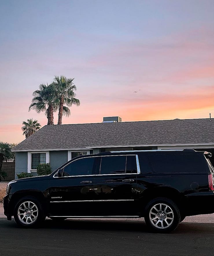 Black luxury SUV waiting under a Spanish-tile porte-cochere with a saguaro and palm at a Scottsdale resort